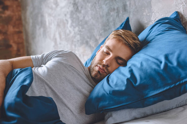 close up view of young man sleeping in bed at home 