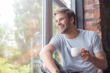 Windows'da seyir ve pencere üzerinde kahve ile oturan gülümseyen adam 