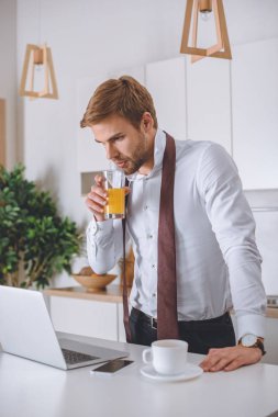 taze meyve suyu içme ve sabah süre içinde laptop perde mutfak at bakarak genç işadamı 