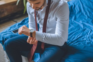 beyaz gömlek ve kravat kol saati evde yatak odasında koyarak boyun üzerinde işadamı seçici odak