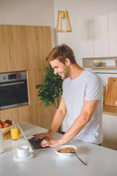 Jovem Sorrindo Usando Laptop Mesa Cozinha Com Café Manhã — Fotografia de Stock Grátis