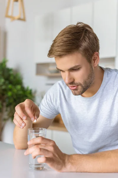 Young Man Putting Pill Glass Water Kitchen Table — Stock Photo, Image
