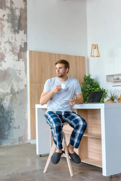 Young Man Drinking Coffee Looking Away Table Laptop — Stock Photo, Image