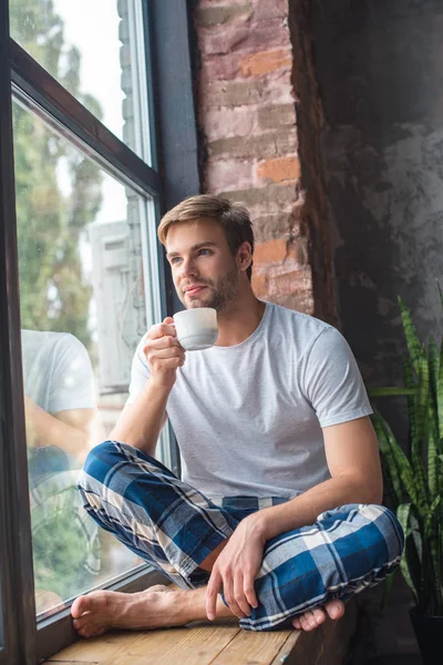 Selektywny Fokus Młody Człowiek Siedząc Filiżanką Kawy Parapecie — Zdjęcie stockowe