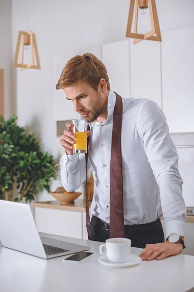 Young Businessman Drinking Fresh Juice Looking Laptop Screen Kitchen Morning — Stock Photo, Image