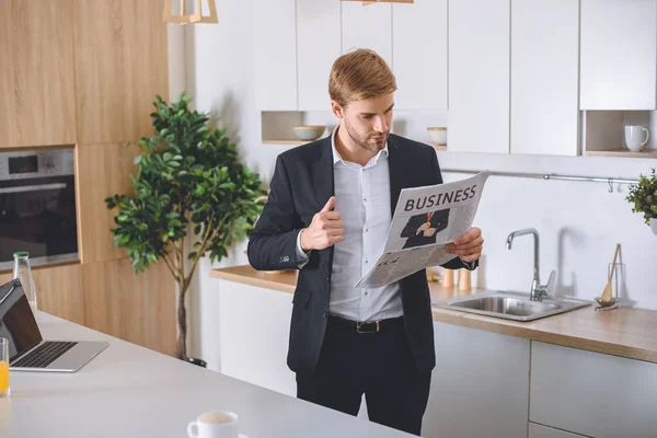 young businessman reading business newspaper at kitchen