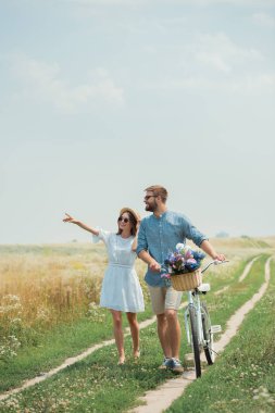 kır çiçekleri ile yaz alanında retro Bisiklet ile gülümseyen çift güneş gözlüğü