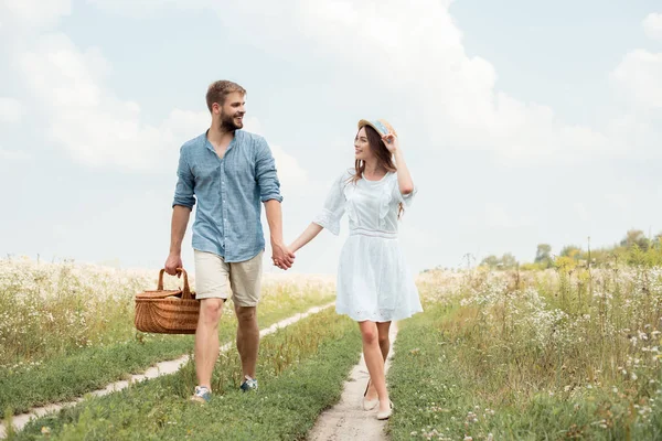 Leende Par Med Picknickkorg Hålla Händerna Medan Promenader Fältet — Stockfoto