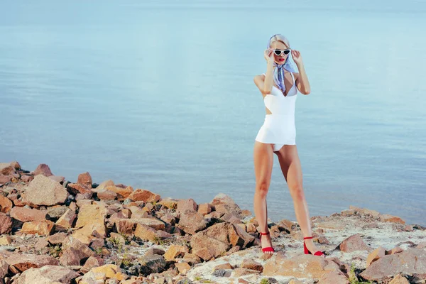 迷人的年轻女子摆在岩石海滩白色复古泳装 — 图库照片
