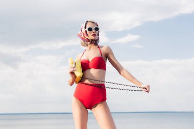 kırmızı bikini ve ipek eşarp deniz kenarında sarı telefon ile poz moda model