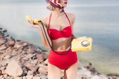 kayalık plaj döner telefon ile poz kırmızı bikini kız görünümünü kırpılmış