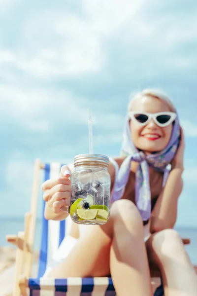 Selective Focus Smiling Woman Holding Mason Jar Lemonade Sitting Beach — Free Stock Photo