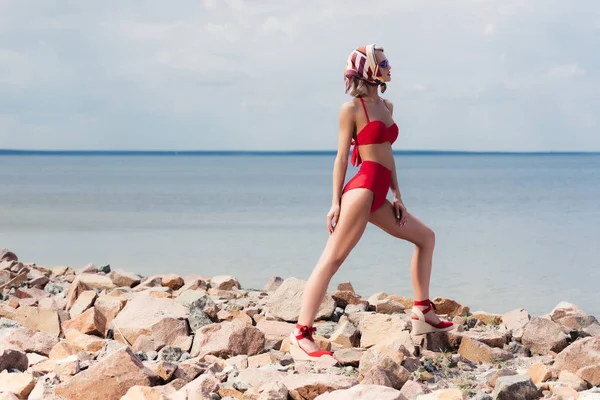 时尚的年轻女子摆在岩石海滩复古红比基尼 — 图库照片