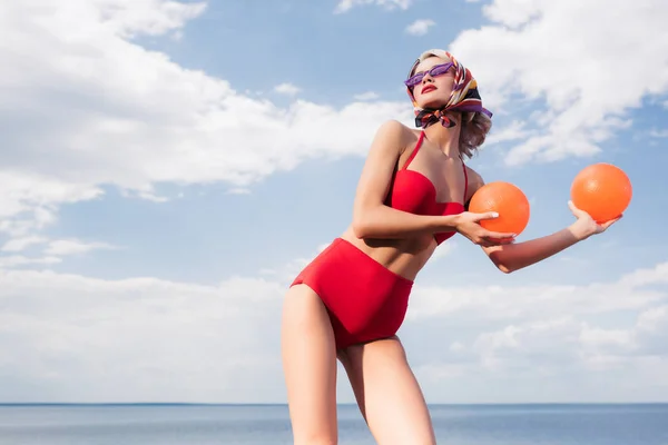 Stylisches Model Roten Bikini Sonnenbrille Und Seidenschal Posiert Mit Bällen — kostenloses Stockfoto