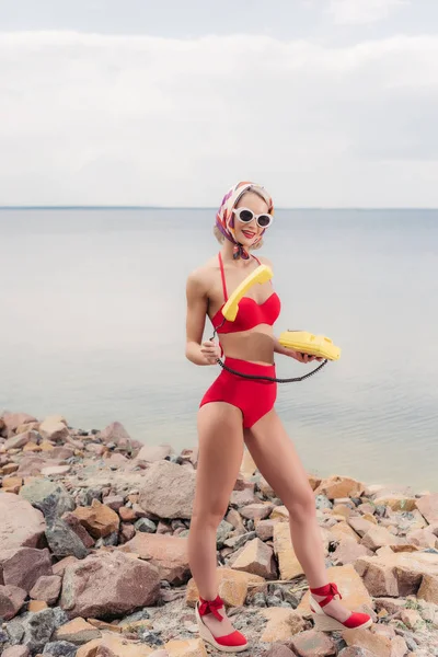 Jolie Femme Bikini Vintage Rouge Posant Avec Téléphone Rotatif Jaune — Photo gratuite