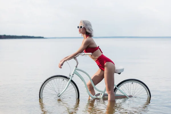 Piękne Modne Dziewczyny Czerwonym Bikini Siedząc Rowerze Wodzie — Zdjęcie stockowe