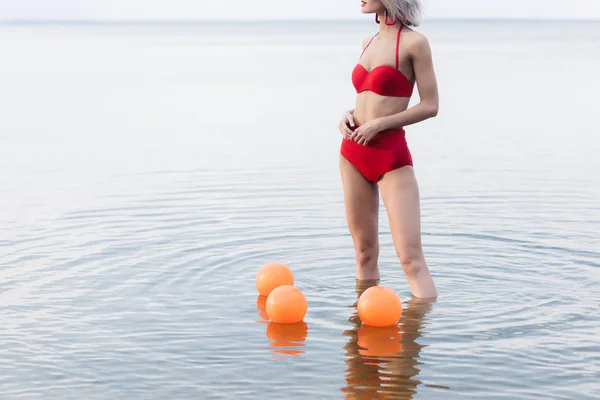 Обрезанный Вид Женщины Винтажном Красном Бикини Стоящей Морской Воде Оранжевыми — Бесплатное стоковое фото