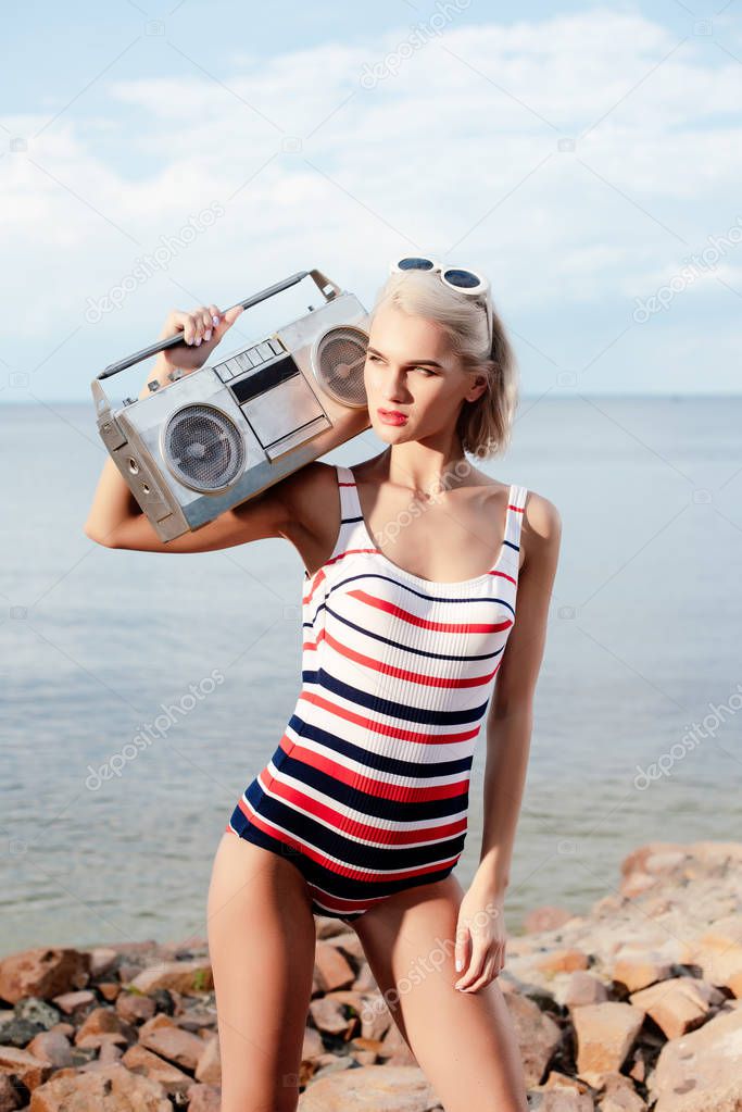 beautiful blonde woman in vintage swimsuit posing with cassette recorder