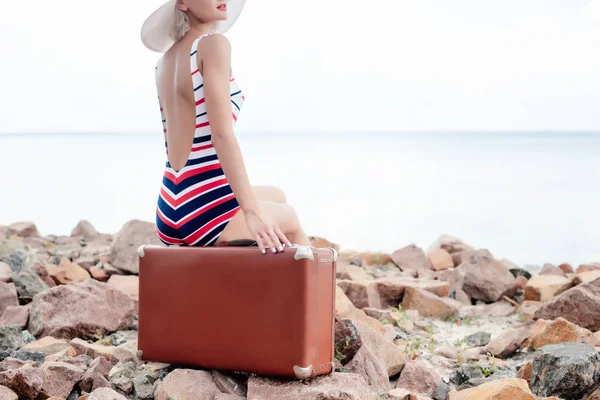 Cropped View Stylish Woman Striped Swimsuit Sitting Luggage Rocky Beach — Stock Photo, Image