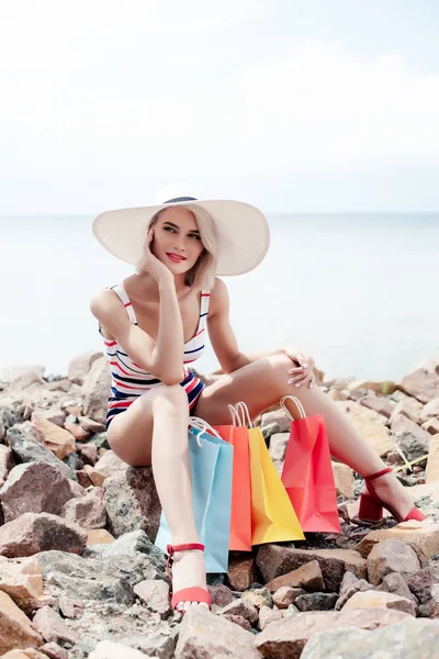 Aantrekkelijk Meisje Witte Hoed Zittend Rotsen Met Shopping Tassen — Stockfoto