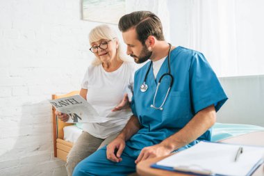 üst düzey kadın bakım evinde seyahat gazete okuma bakarak stetoskop ile genç doktor