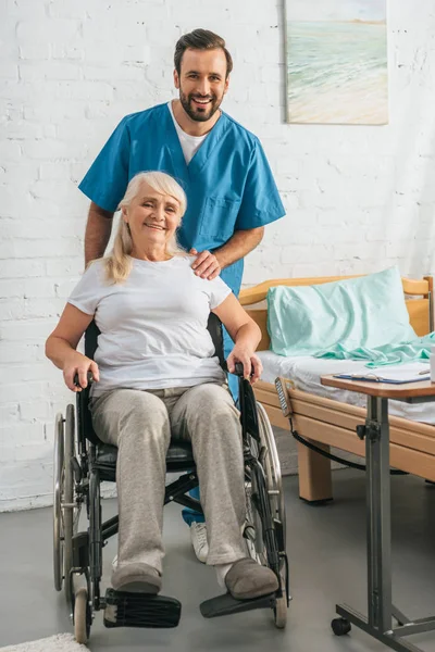 Fröhliche Junge Krankenschwester Und Glückliche Seniorin Rollstuhl Die Die Kamera — Stockfoto