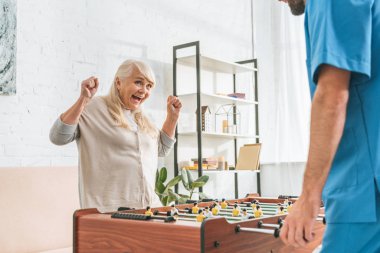 Erkek hemşire ve heyecanlı kadın kıdemli masa futbol kırpılmış 