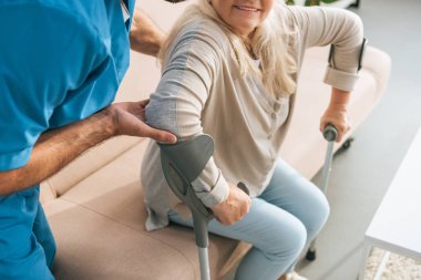 cropped shot of male nurse supporting senior woman with crutches  clipart