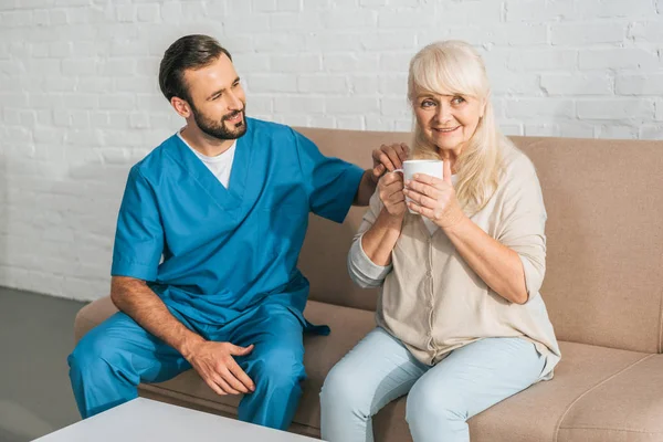 Glimlachend Verzorger Kijken Gelukkig Senior Vrouw Drinken Tea — Stockfoto