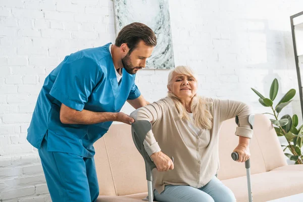 Jonge Verpleger Ter Ondersteuning Van Senior Vrouw Met Krukken — Stockfoto