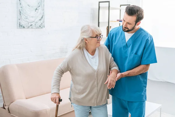 Male Nurse Supporting Senior Woman Eyeglasses Walking Stick — Stock Photo, Image