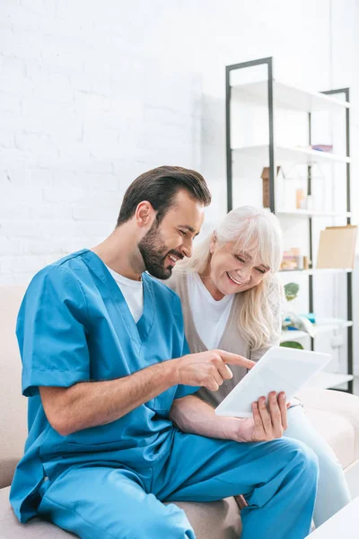 Gelukkig Senior Vrouw Jonge Verpleger Digitale Tablet Samen Gebruiken — Stockfoto