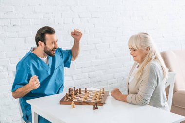 neşeli genç adam ve birlikte satranç oynayan odaklı üst düzey kadın