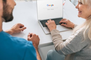 Genç adam ve google web sitesinde ekran ile dizüstü bilgisayar kullanarak gülümseyen kadın kıdemli kırpılmış atış 