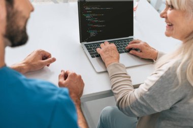 Genç adam ve gülümseyen kadın kıdemli ekran html kodu içeren dizüstü kullanarak kırpılmış atış
