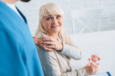ilacı ve caregiver elini tutarak gülümseyen kadın kıdemli