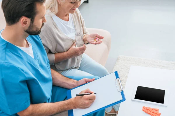 Hoge Hoekmening Van Verpleger Schrijven Klembord Senior Vrouw Met Pillen — Stockfoto