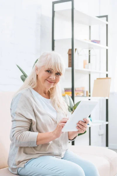 Lycklig Senior Kvinna Använder Digitala Tablett Och Ler Mot Kameran — Gratis stockfoto