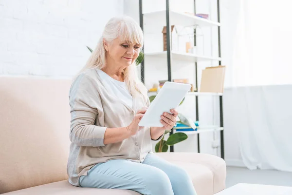 Leende Senior Kvinna Använda Digitala Surfplatta Medan Sitter Soffan — Stockfoto