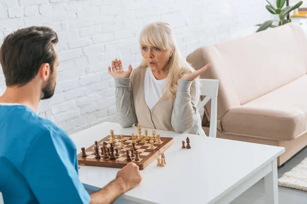 Shocked Senior Woman Playing Chess Young Social Worker — Free Stock Photo