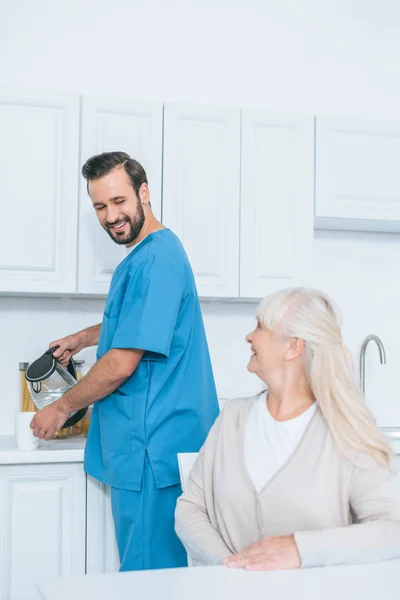 Happy Senior Woman Looking Caregiver Pouring Hot Beverage Mug — Stock Photo, Image