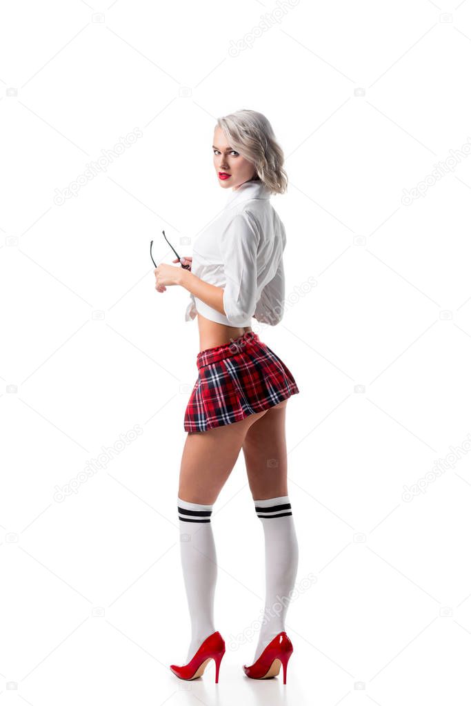 side view of sexy young woman in short schoolgirl plaid skirt and knee socks with eyeglasses posing isolated on white