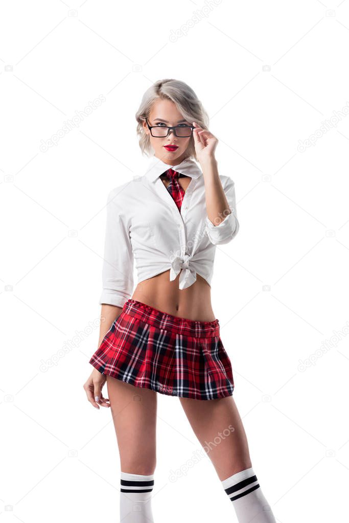 portrait of seductive blond woman in schoolgirl clothing and eyeglasses looking at camera isolated on white