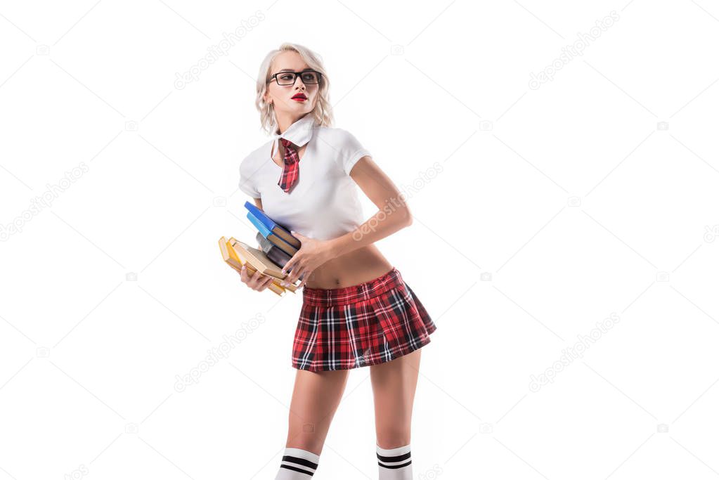 sexy blond woman in schoolgirl clothing holding pile of books isolated on white