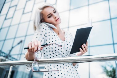 El smartphone Caddesi üzerinde konuşurken defter ile genç işkadını seçici odak