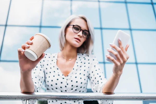 通りにスマート フォンを使用して行くにコーヒーと眼鏡の焦点を当てた女性実業家  — 無料ストックフォト