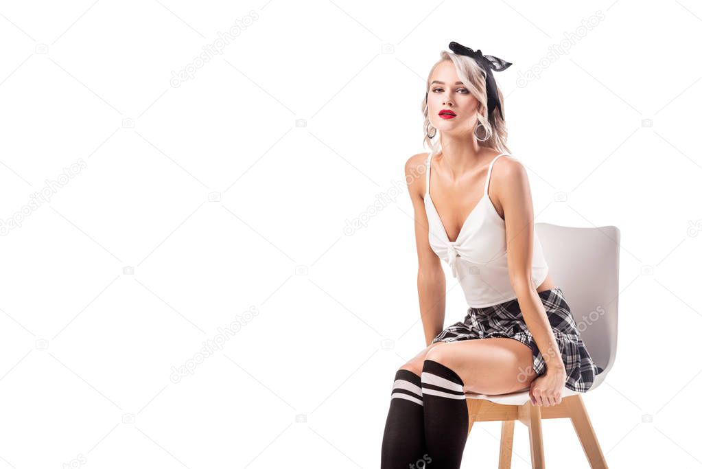 sexy blond woman in short plaid skirt and knee socks sitting on chair isolated on white