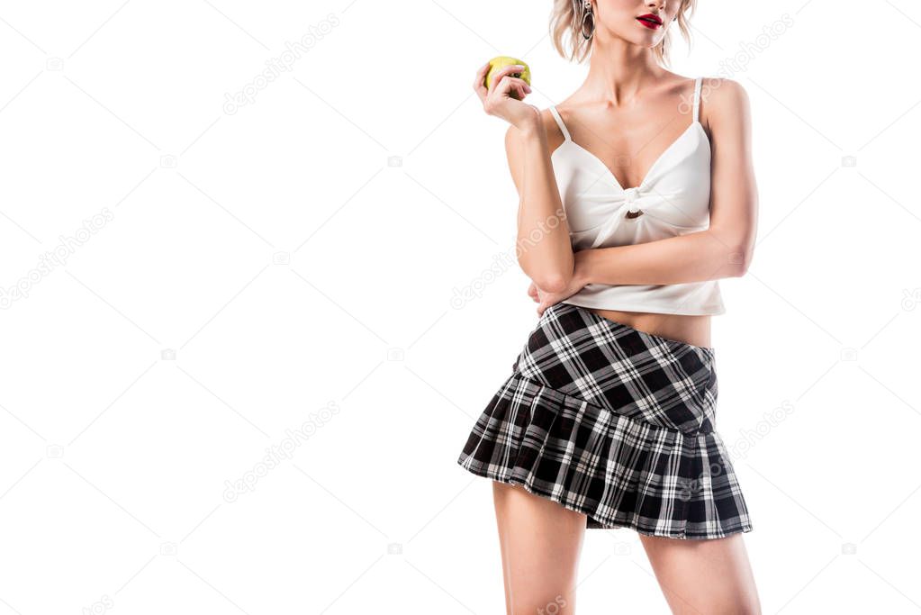 partial view of woman in seductive college clothing holding fresh apple in hand isolated on white