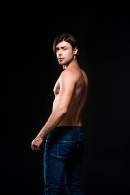 arkadan görünüşü gömleksiz erkek kot pantolon siyah izole kamera bakıyor