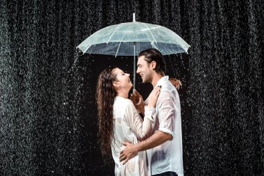 romantik çift beyaz gömlek siyah izole yağmur damlaları altında şemsiyesi altında ayakta yan görünüm